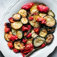 baked tomatoes and zucchini on a white plate