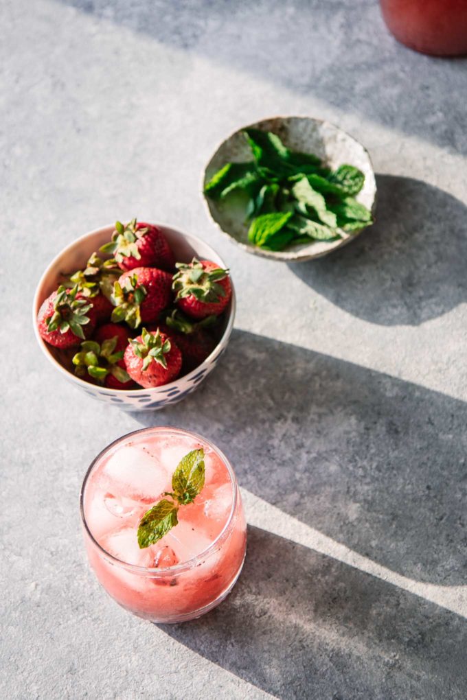 strawberries, mint, and a water spritzer on a blue table