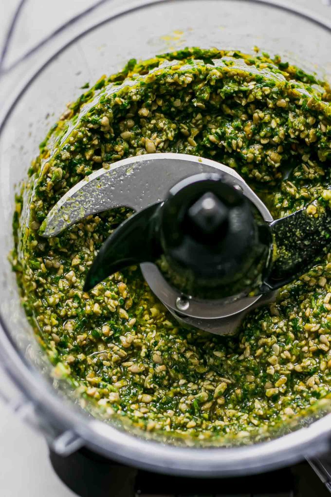 close up of processed pesto ingredients in a food processor