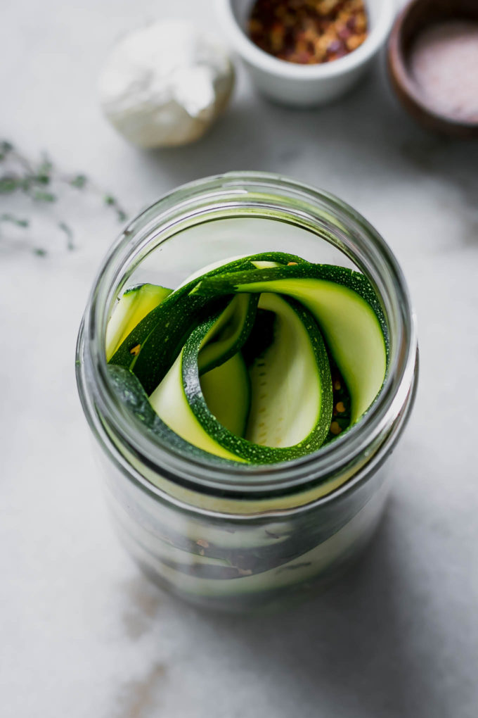 zucchini slices in a pickling jar on a white table