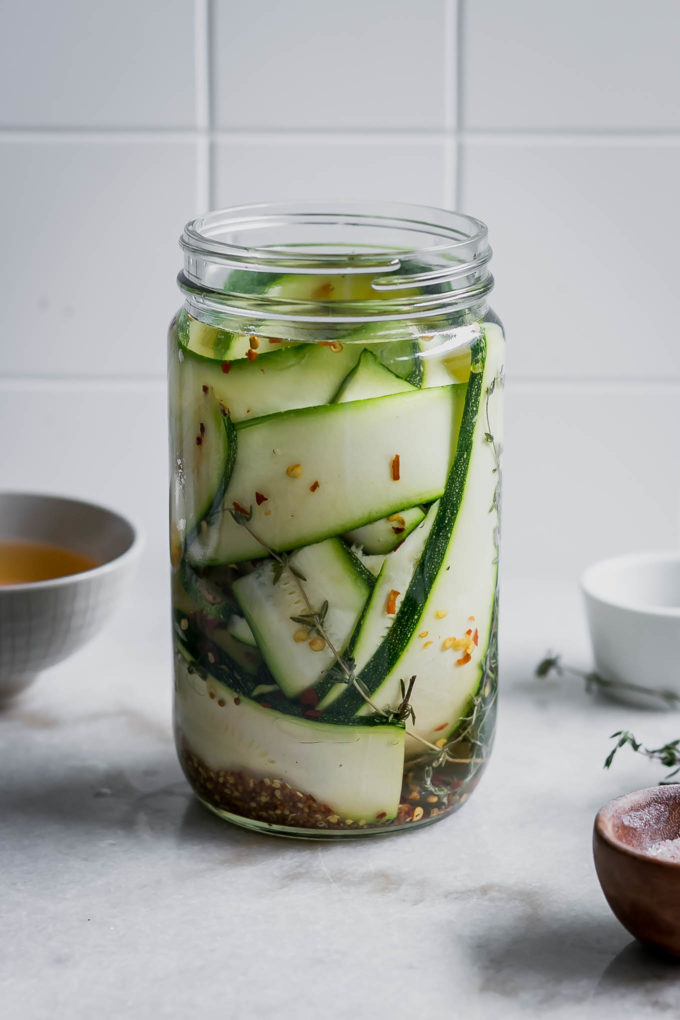 zucchini slices in a pickling jar on a white countertop