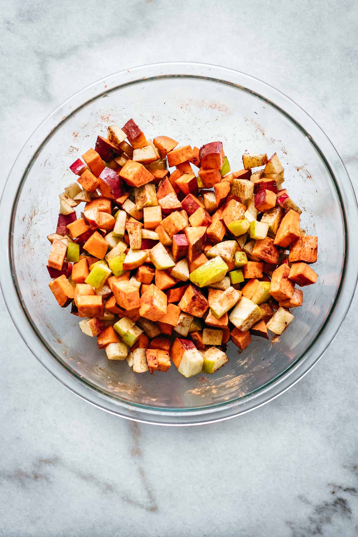 diced sweet potatoes and apples in a glass bowl with cinnamon and salt
