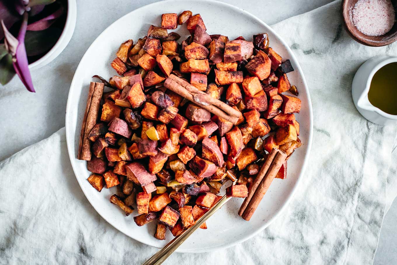 roasted apples and sweet potatoes on a white plate with a gold fork