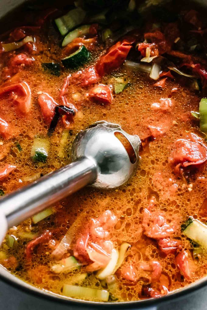 an immersion blender inside a pot of tomato soup