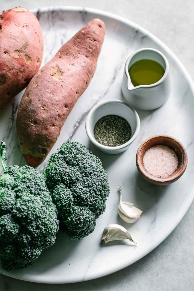 sweet potatoes, broccoli, olive oil, salt, pepper, and garlic on a white tray