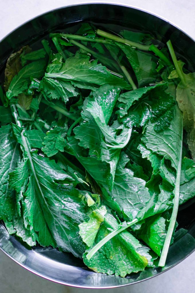 turnip greens submerged in a bowl of water