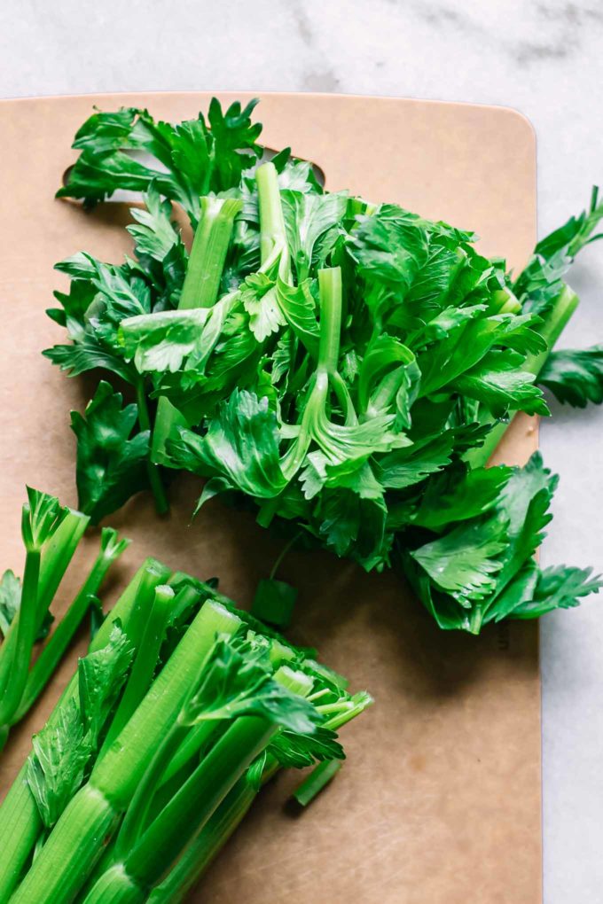 cut celery leaves on a wood cutting board