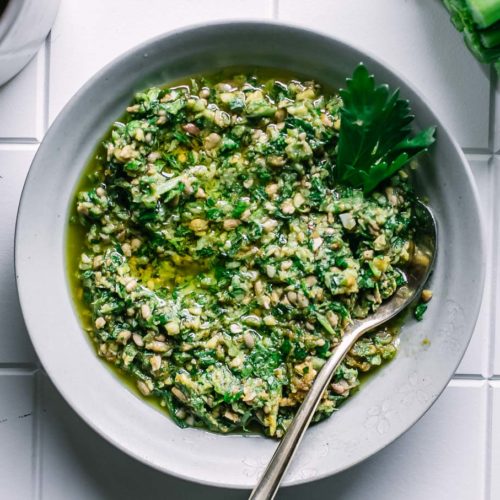 celery greens pesto in a small white bowl on a white table