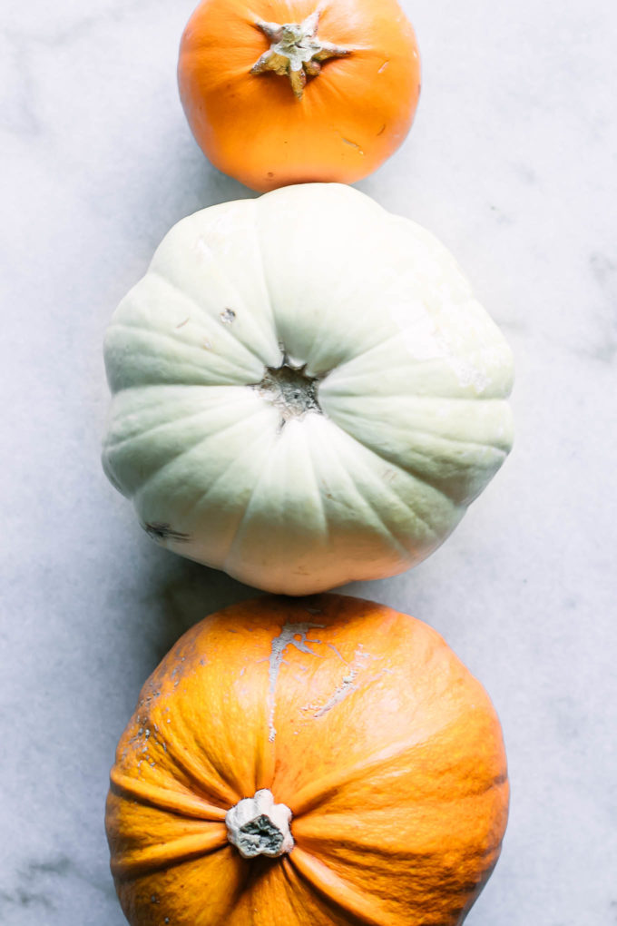 three pumpkins lined up vertically on a marble countertop