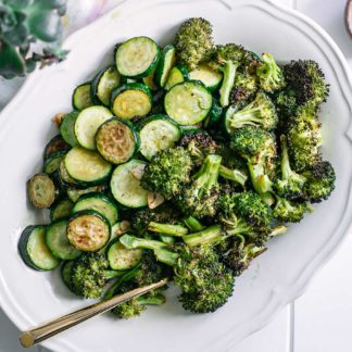 baked zucchini and broccoli side dish with a gold fork on a white table