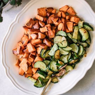 baked sweet potatoes and zucchini side dish on a white table