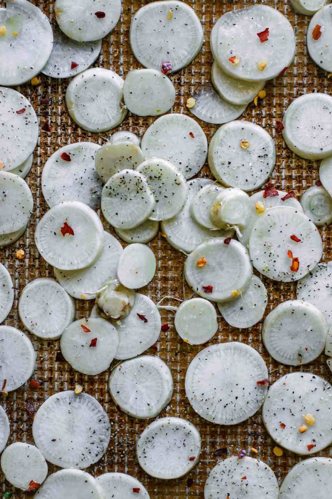 sliced turnips that have been seasoned on a baking sheet