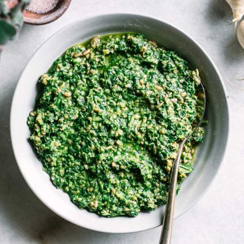 turnip greens pesto in a white bowl on a white marble countertop