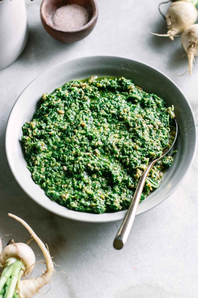 turnip greens pesto in a bowl with turnips in the background