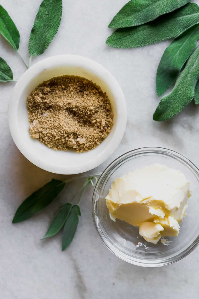 bowls of butter and brown sugar on a white countertop with fresh sage leaves