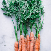 carrots with long carrot leaves on a marble countertop