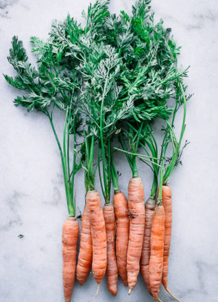 carrots with long carrot leaves on a marble countertop
