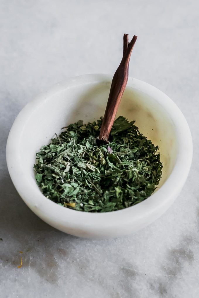 dried guascas herb in a small white bowl with a wooden spoon