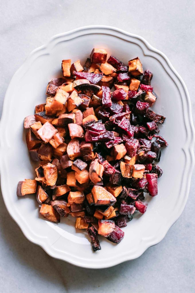 a white plate with baked cut sweet potatoes and red beets