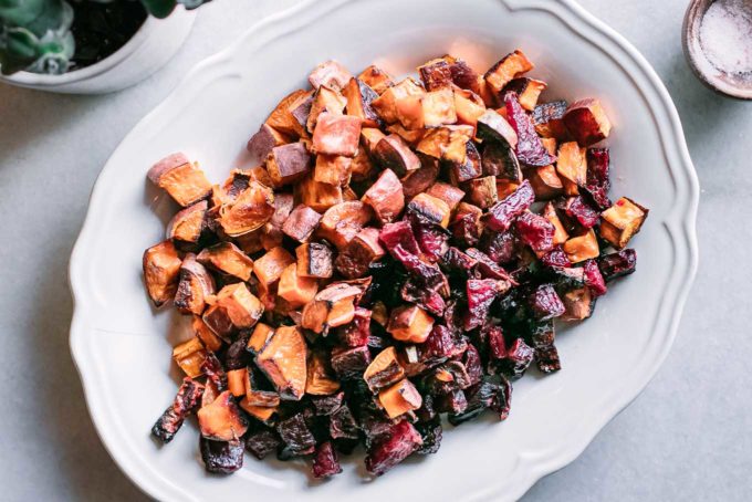 baked beets and sweet potatoes on a white serving plate on a white table