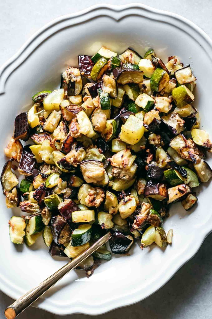 baked zucchini and eggplant on a serving dish with a gold fork