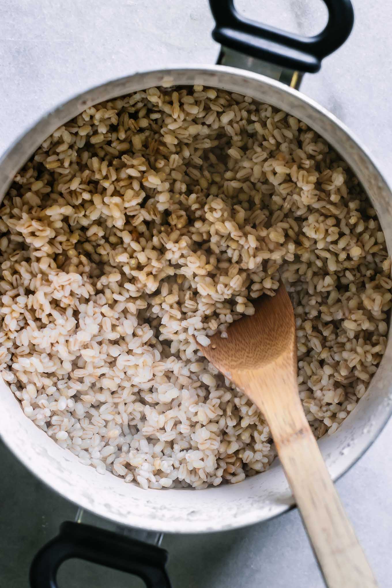 a pan of cooked barley with a wooden spoon