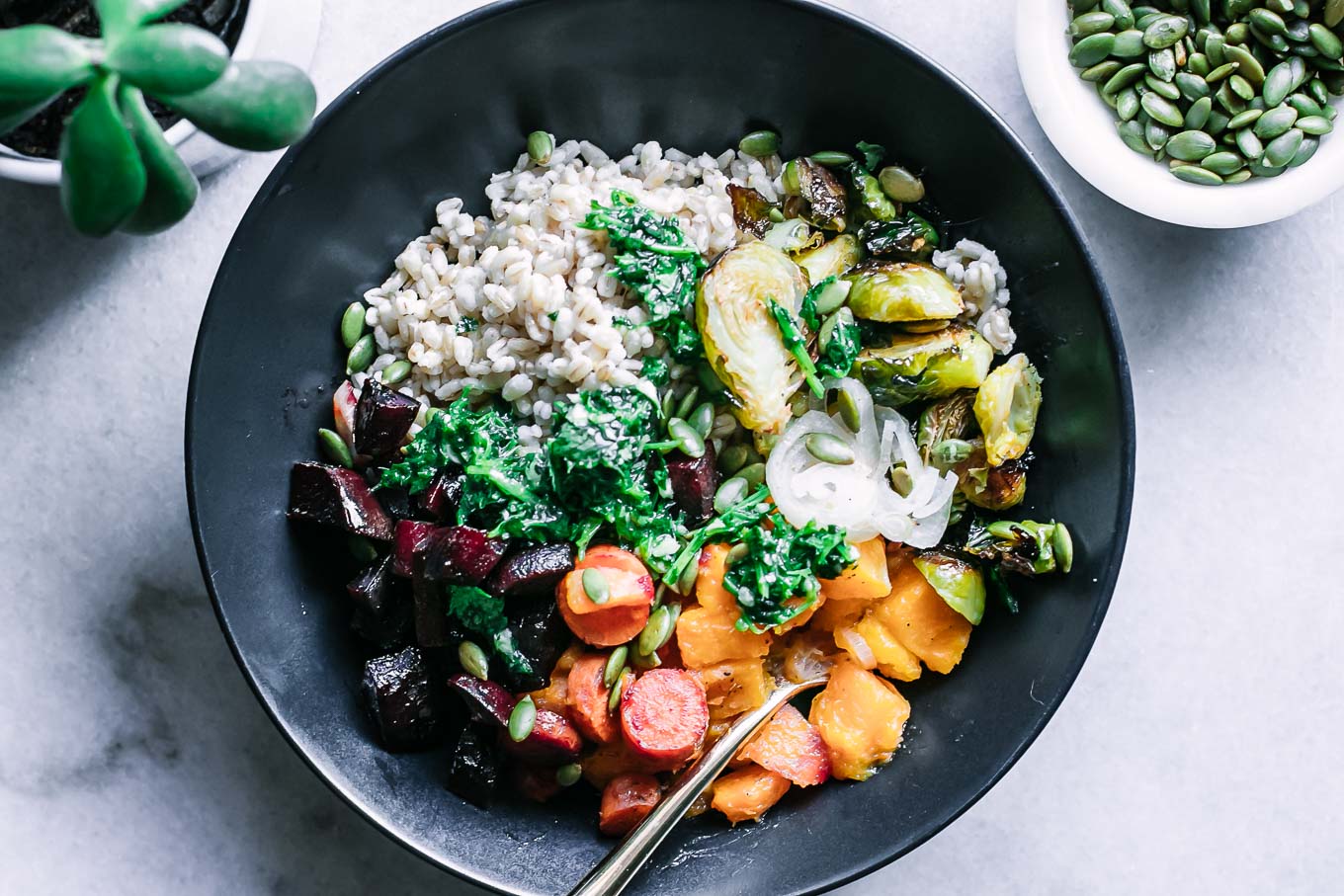 a roasted vegetable barley bowl with garlic herb sauce drizzled on top
