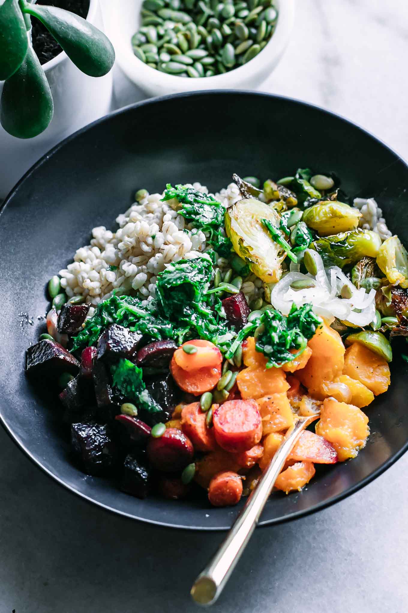 a close up photo of the roasted vegetable barley bowl with herb garlic sauce