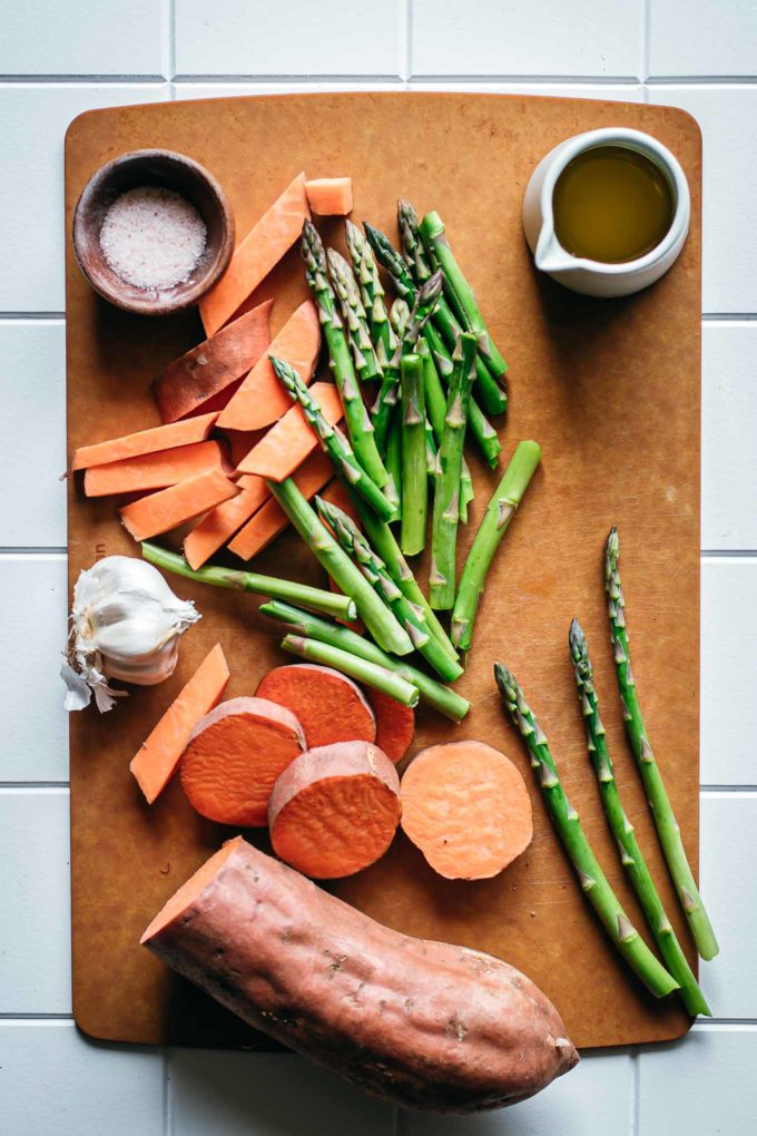 sliced sweet potatoes and asparagus on a wooden cutting board