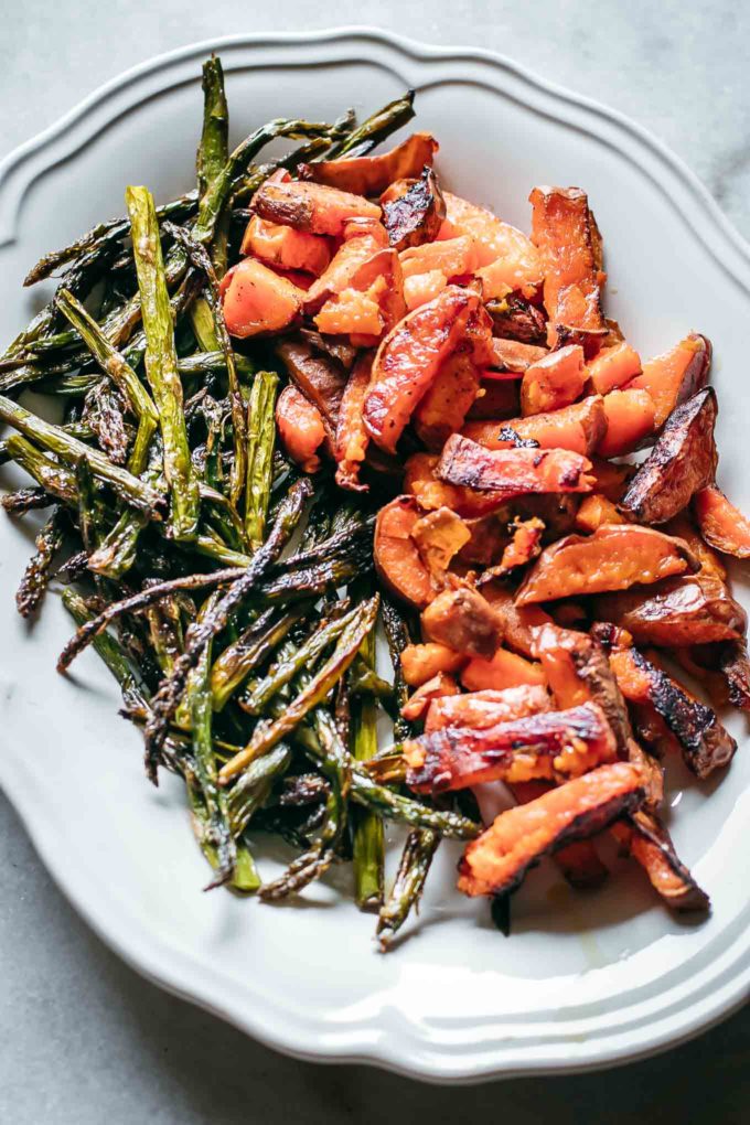 baked asparagus and sweet potatoes on a white plate on a white table