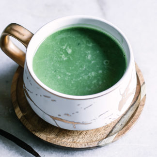 a matcha milk latte with vanilla beans on a white table