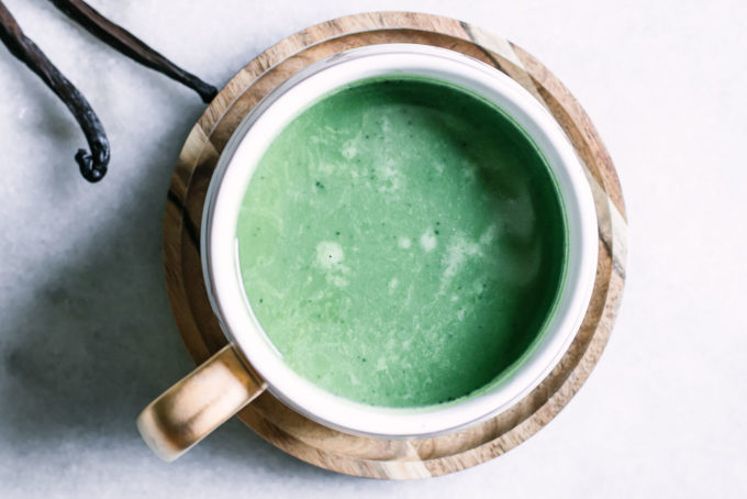 a green matcha latte with vanilla beans in a white mug