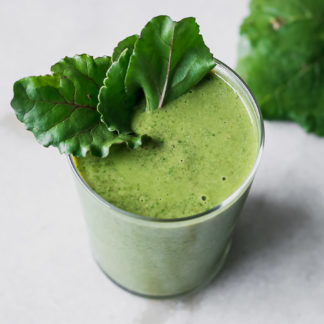a green beet leaves smoothie in a glass on a white table
