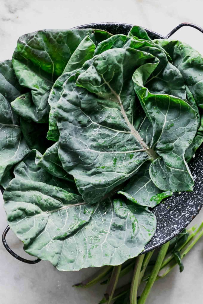 washed brussels sprouts leaves in a colander on a white table