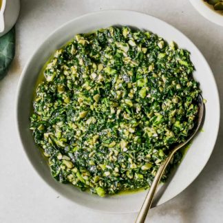 a bowl of brussels sprouts leaves pesto on a white table
