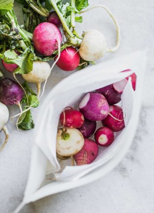 fresh radishes stored in a freezer bag on a white table