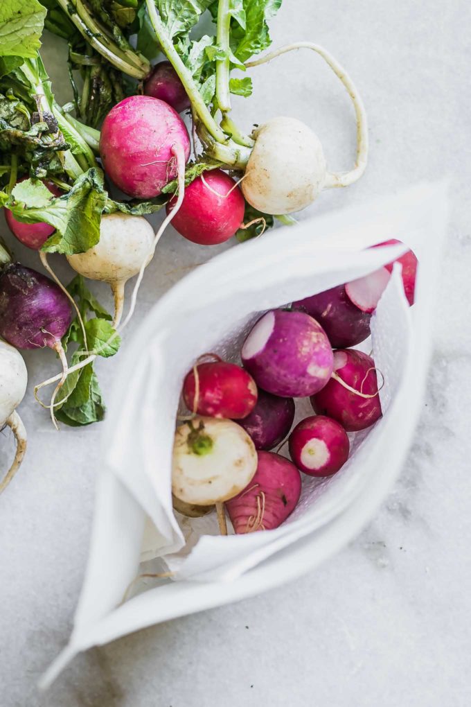 fresh radishes stored in a freezer bag on a white table