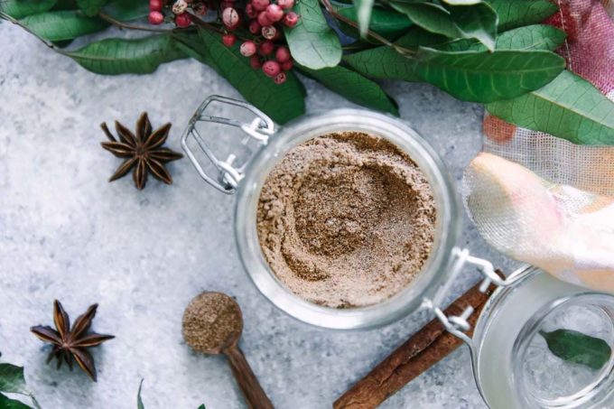 a small glass jar filled with homemade masala chai spices on a blue table