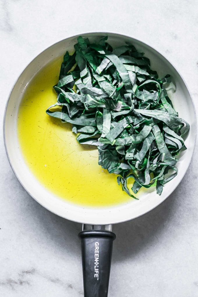 olive oil and sliced brussels sprouts greens in a white saucepan