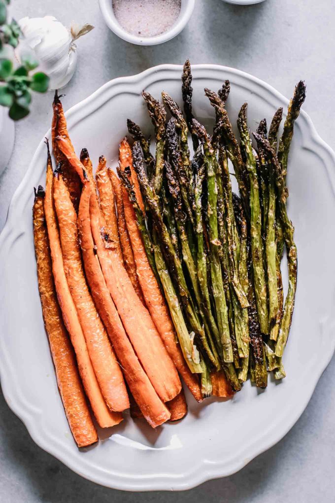 baked asparagus and carrots on a white plate on a white table