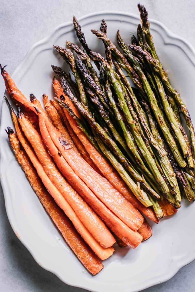 cut carrots and asparagus after roasting on a white serving dish