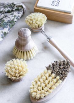 four wooden kitchen dish brushes on a white countertop