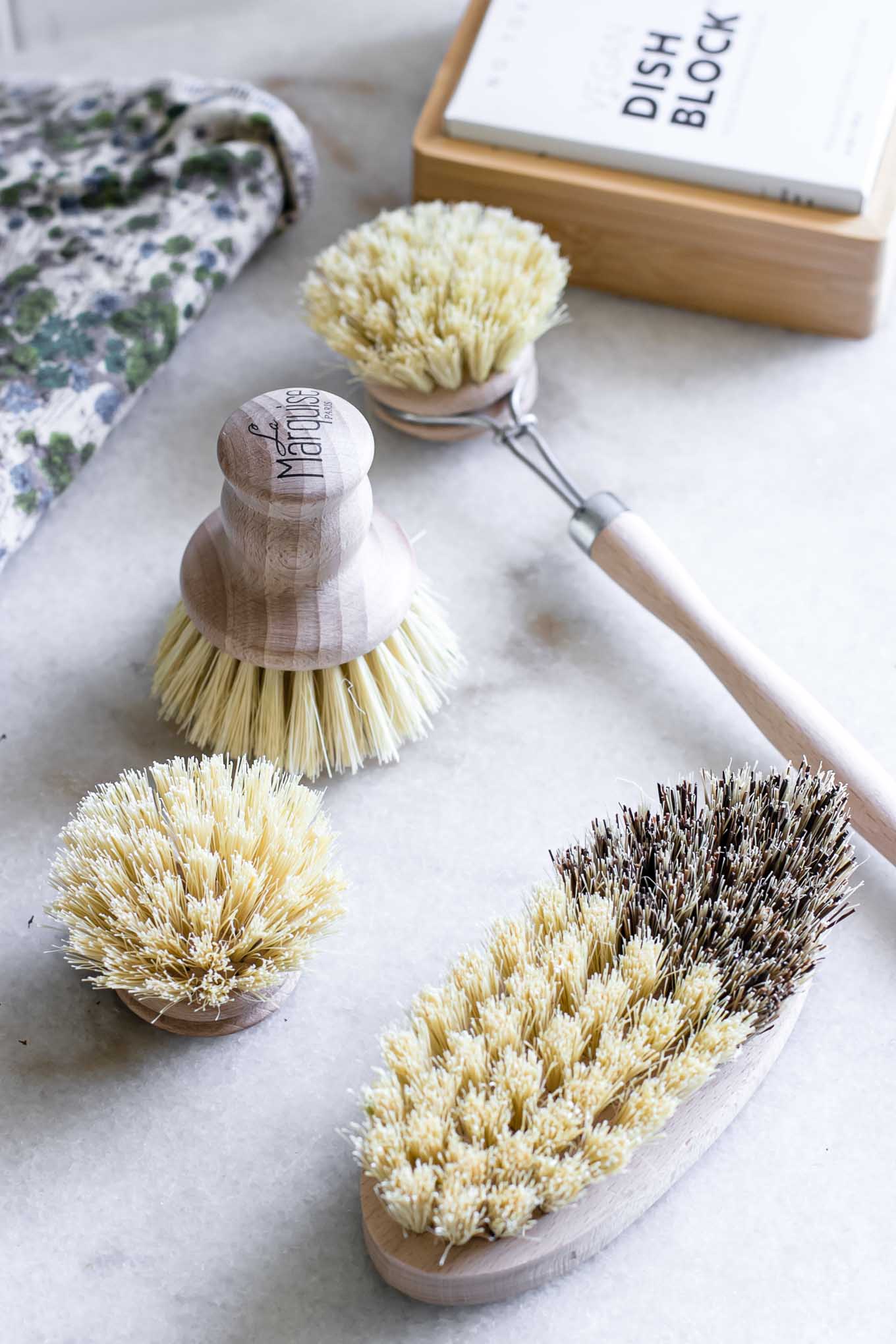 four wooden kitchen dish brushes on a white countertop