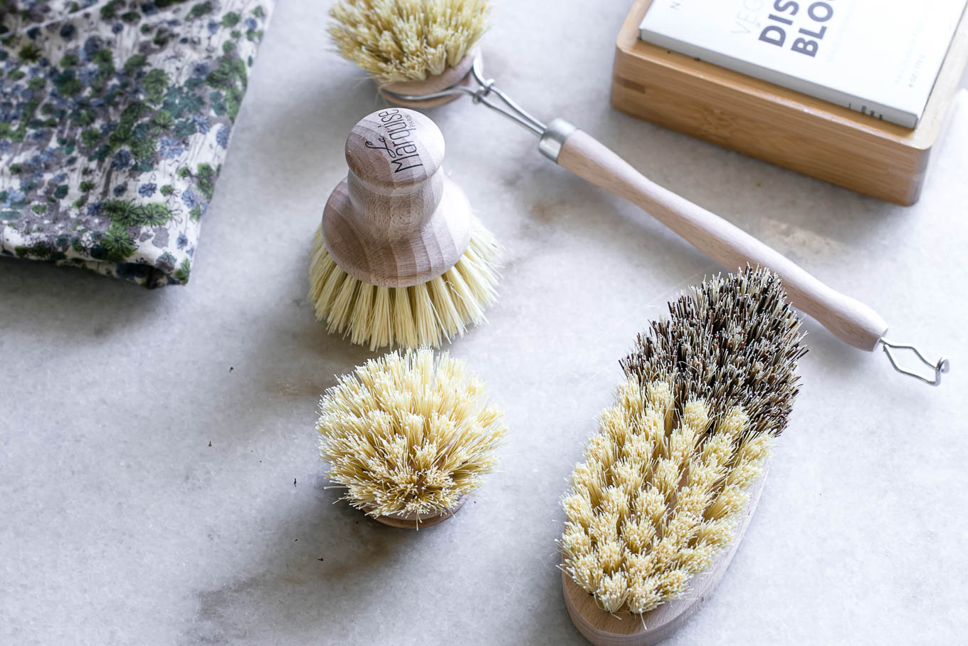 wooden dish brushes, reusable dish rags, and natural dish scours on a white countertop