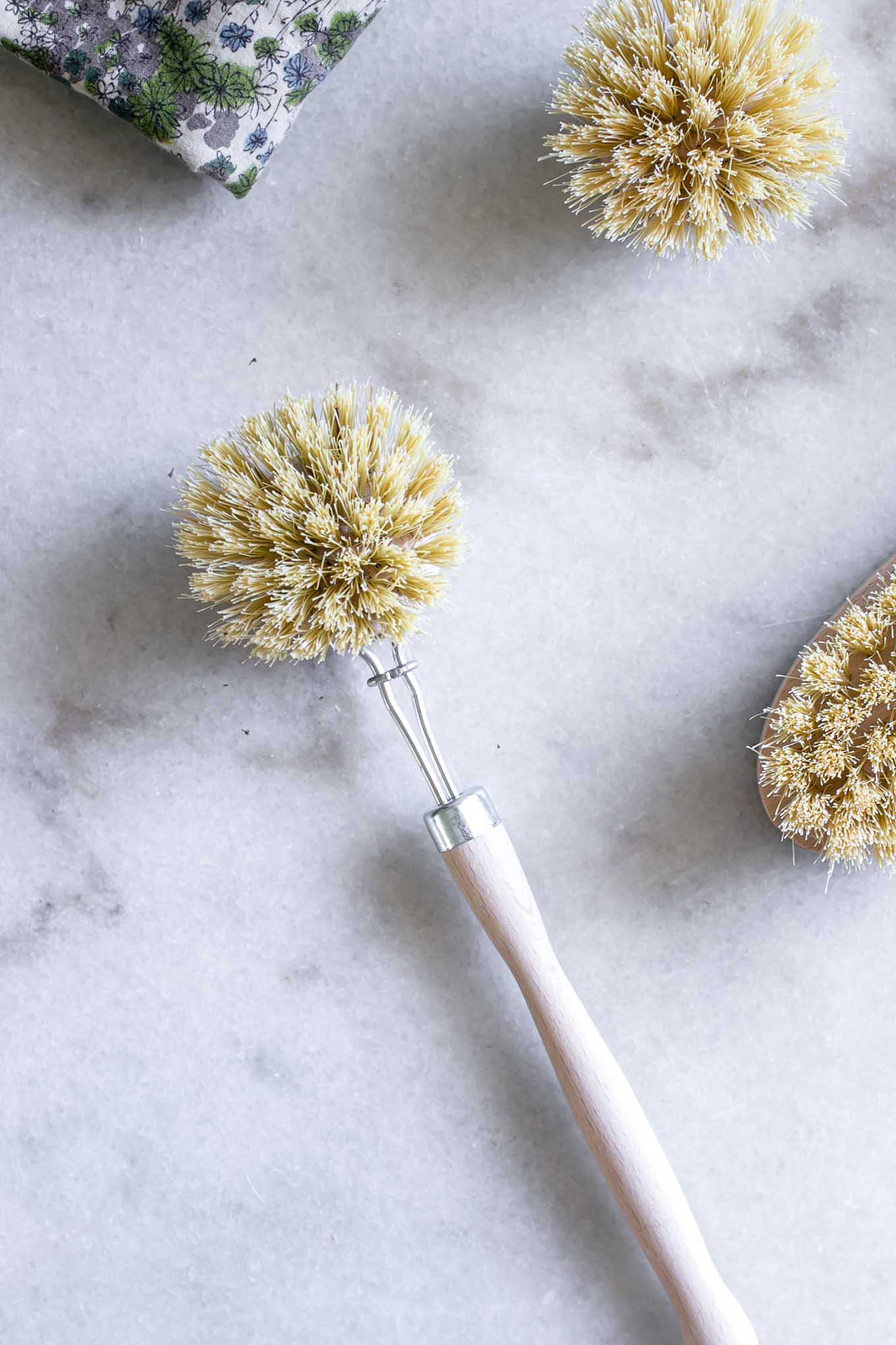 a wooden dish brush on a white marble countertop