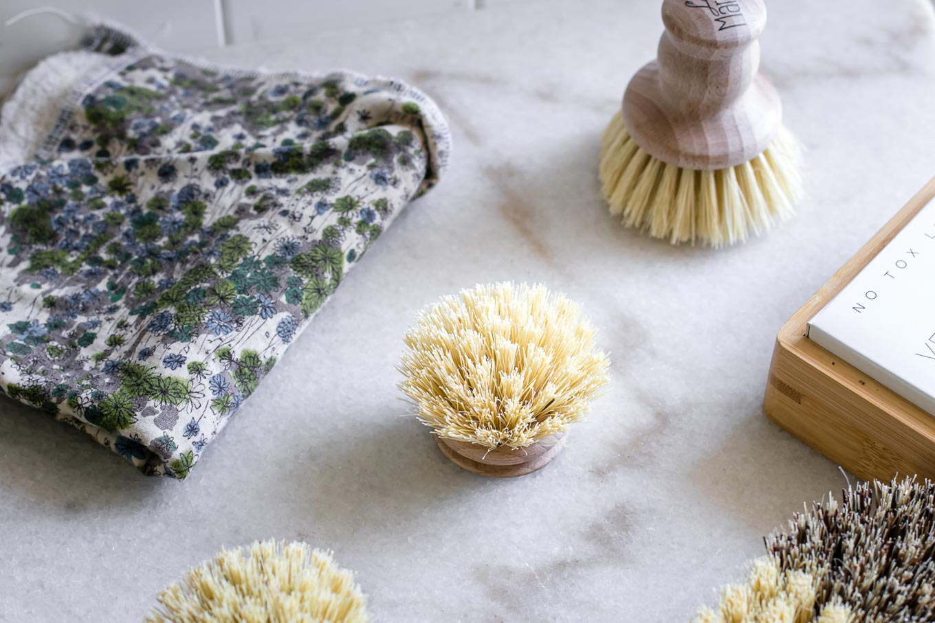 wooden dish brushes on a white countertop with a dish rag