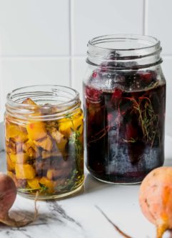 red and golden beets inside picking jars with herbs and brine