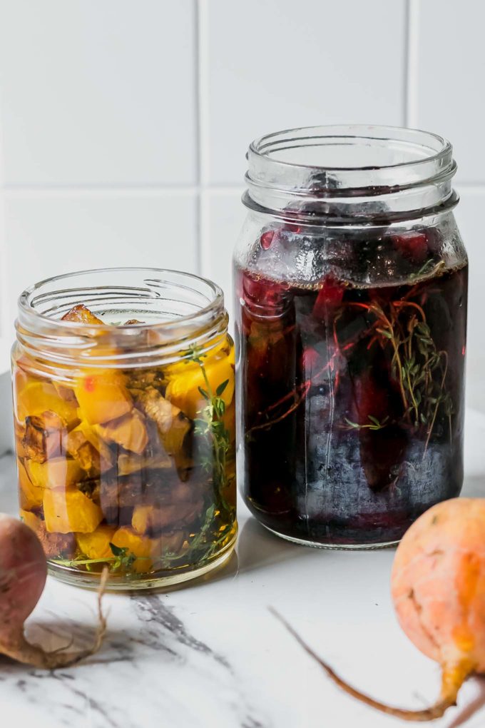 red and golden beets inside picking jars with herbs and brine