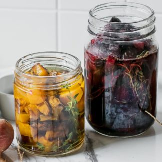 two jars of refrigerator pickled red and golden beets on a white table