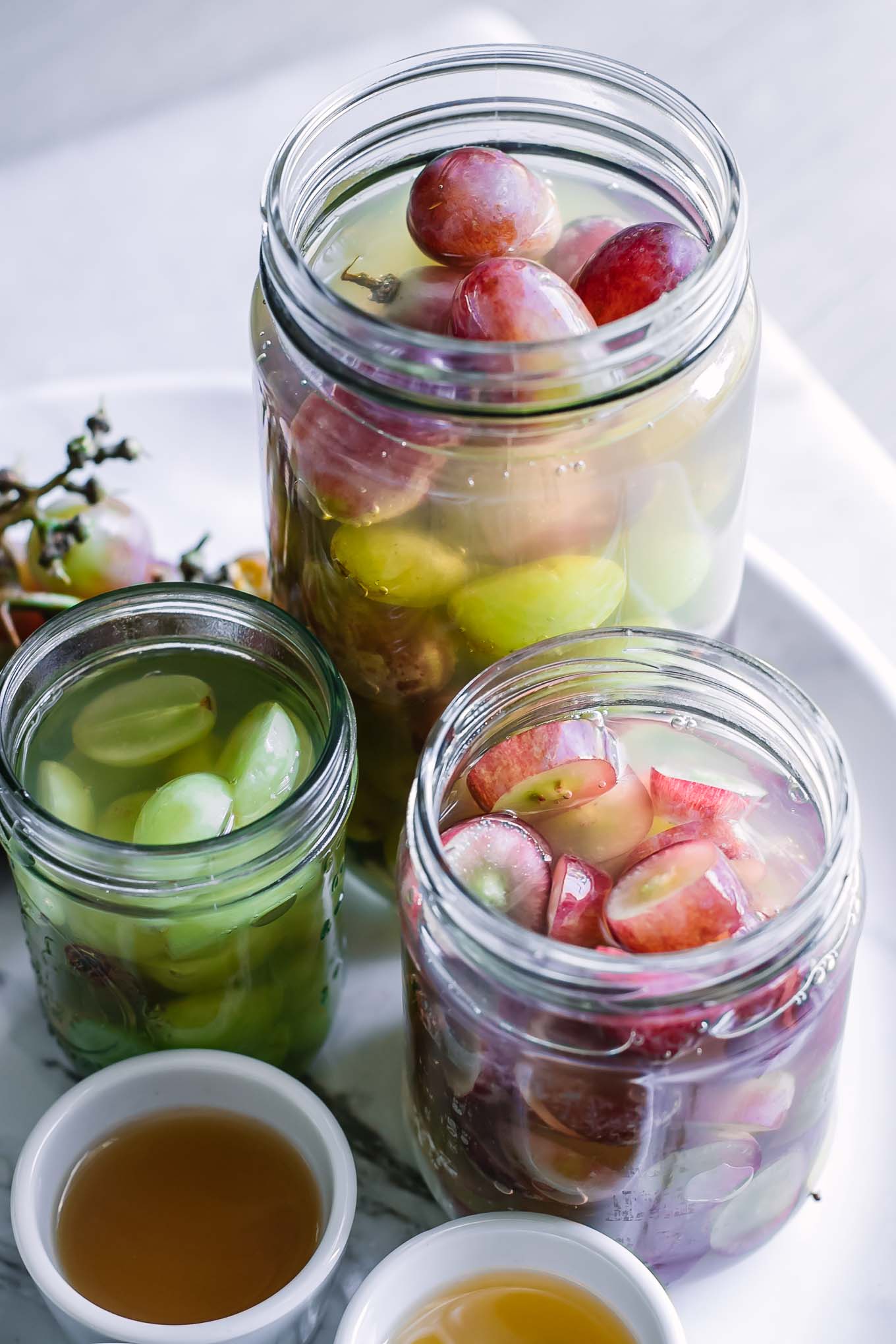 jars of grapes in pickling brine on a white table